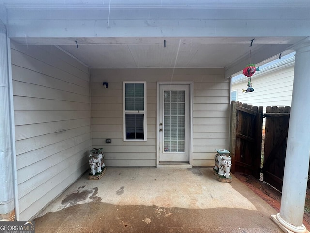 view of exterior entry with a patio and fence