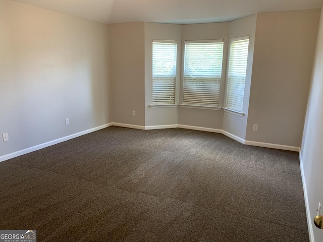 empty room with dark carpet and baseboards