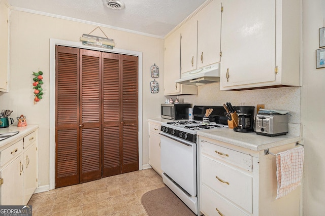 kitchen with visible vents, light countertops, white gas range oven, under cabinet range hood, and stainless steel microwave