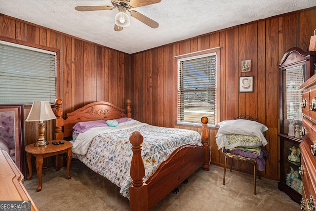 carpeted bedroom with wooden walls, a textured ceiling, and ceiling fan