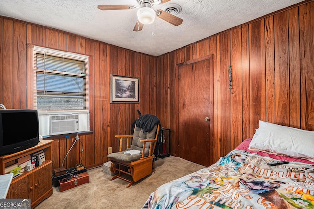 carpeted bedroom with wooden walls, a ceiling fan, and a textured ceiling