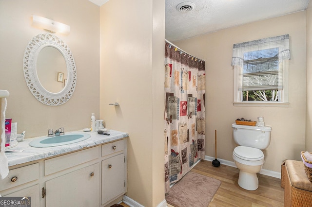 bathroom with visible vents, baseboards, toilet, wood finished floors, and vanity