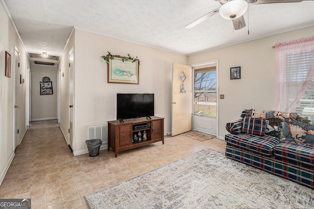 living room with baseboards, visible vents, a textured ceiling, and a ceiling fan