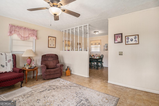 living area featuring baseboards, a textured ceiling, and ceiling fan