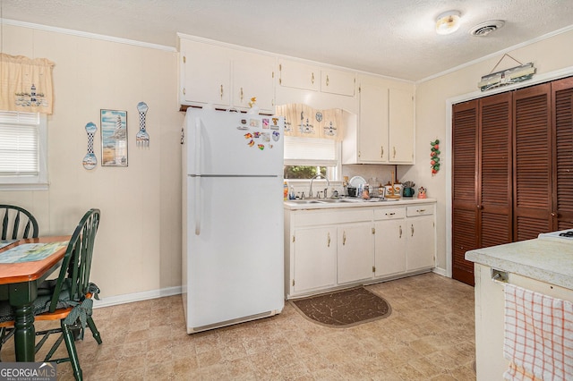 kitchen with light countertops, visible vents, freestanding refrigerator, and ornamental molding