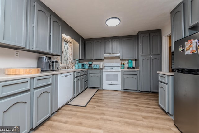 12701 Ga Highway 96 E, Fort Valley, GA 31030 - kitchen with white appliances, under cabinet range hood, light countertops, light wood-style flooring, and gray cabinetry