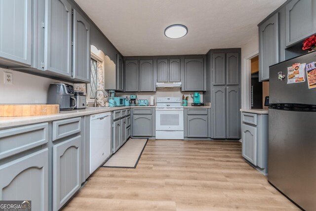 12701 Ga Highway 96 E, Fort Valley, GA 31030 - kitchen with white appliances, under cabinet range hood, light wood-type flooring, gray cabinetry, and light countertops