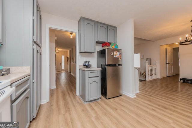 12701 Ga Highway 96 E, Fort Valley, GA 31030 - kitchen with freestanding refrigerator, gray cabinets, light wood-style flooring, light countertops, and a chandelier