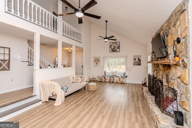 12701 Ga Highway 96 E, Fort Valley, GA 31030 - living room with ceiling fan, high vaulted ceiling, wood finished floors, a stone fireplace, and stairs