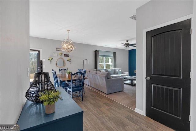 dining room featuring ceiling fan with notable chandelier and wood finished floors