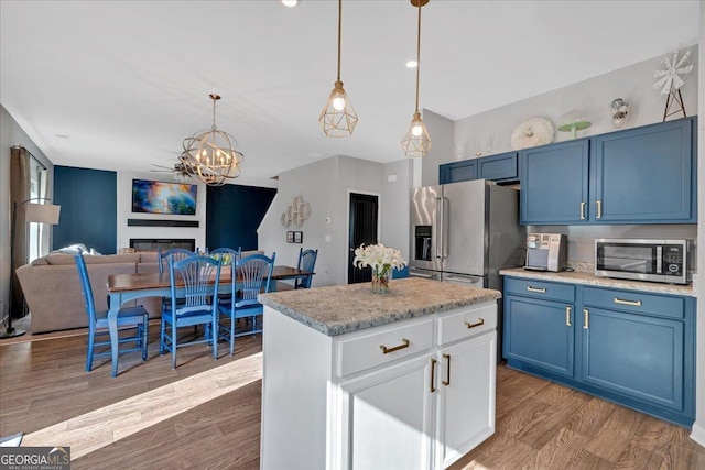 kitchen with a chandelier, decorative light fixtures, wood finished floors, stainless steel appliances, and blue cabinets