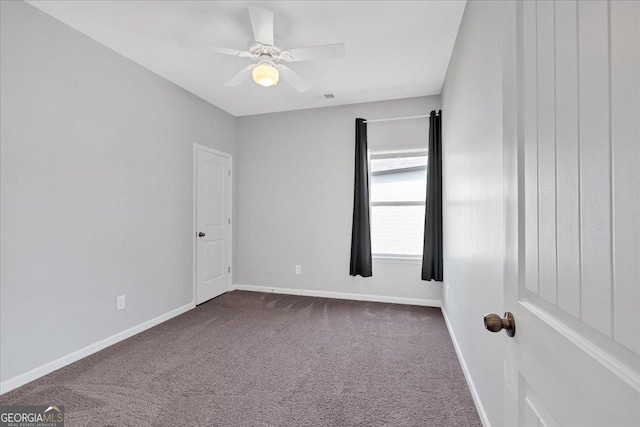 spare room with dark colored carpet, visible vents, baseboards, and ceiling fan