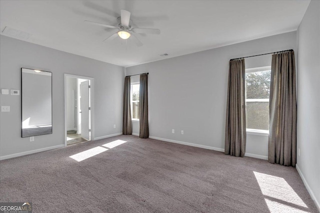 carpeted spare room featuring visible vents, a ceiling fan, and baseboards