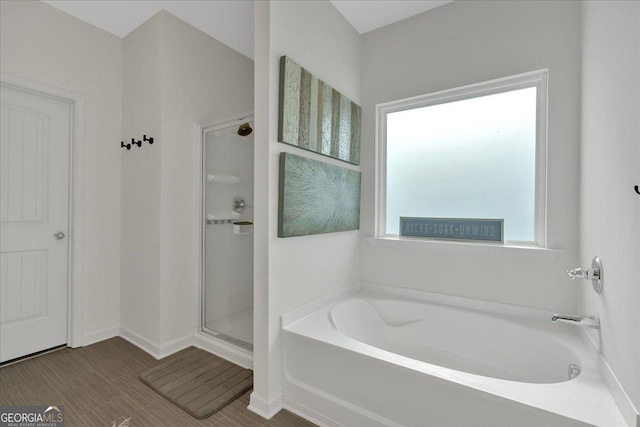 bathroom featuring a bath, a shower stall, and baseboards