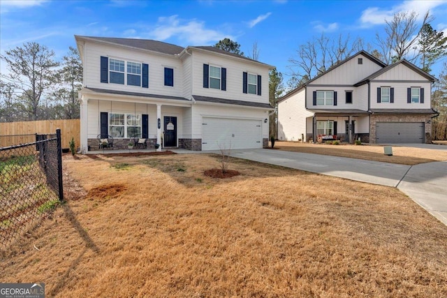 view of front of house with fence, driveway, an attached garage, covered porch, and stone siding