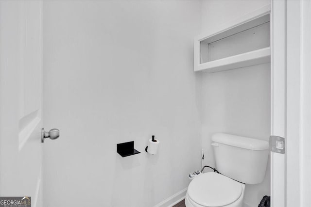 bathroom with baseboards and toilet