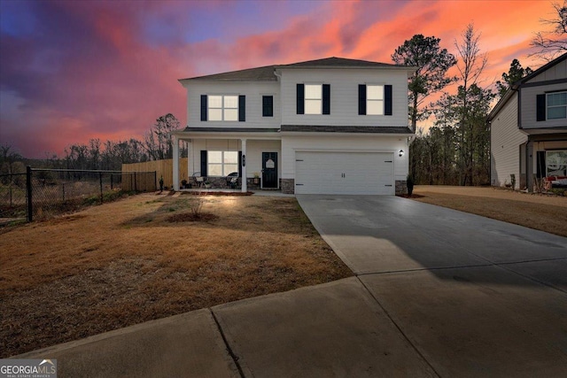 traditional home with fence, driveway, a porch, a garage, and stone siding