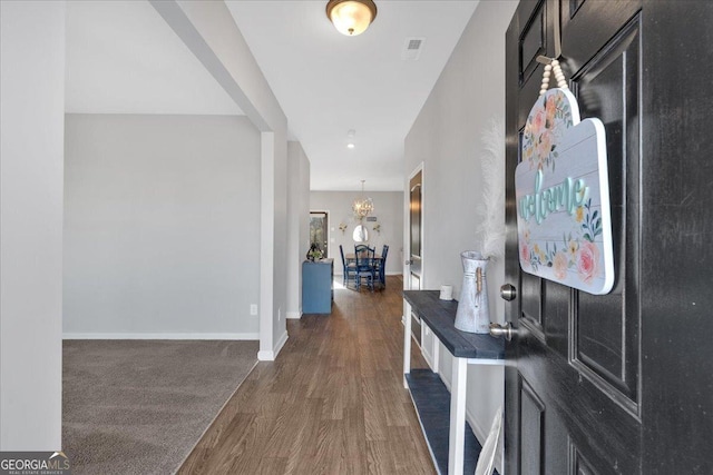 corridor featuring an inviting chandelier, baseboards, and dark wood-style flooring