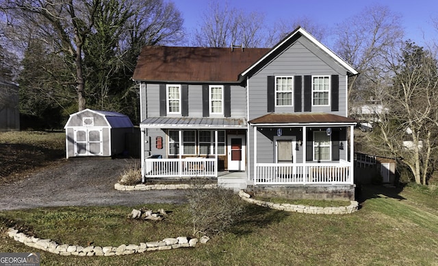 traditional home with a storage unit, an outbuilding, covered porch, and driveway