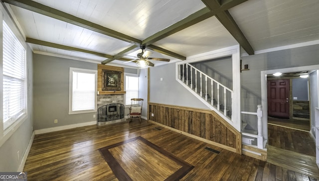 unfurnished living room with stairway, a large fireplace, beamed ceiling, and hardwood / wood-style flooring