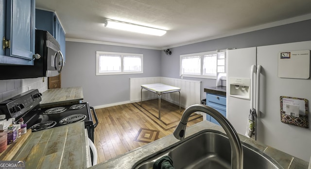 kitchen with blue cabinets, electric range, a sink, wood finished floors, and white fridge with ice dispenser