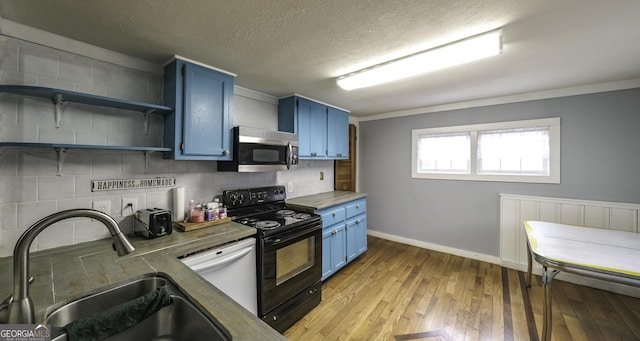 kitchen with stainless steel microwave, blue cabinetry, black range with electric cooktop, dishwasher, and a sink