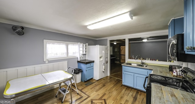 kitchen featuring blue cabinetry, white refrigerator with ice dispenser, black range with electric stovetop, and a sink