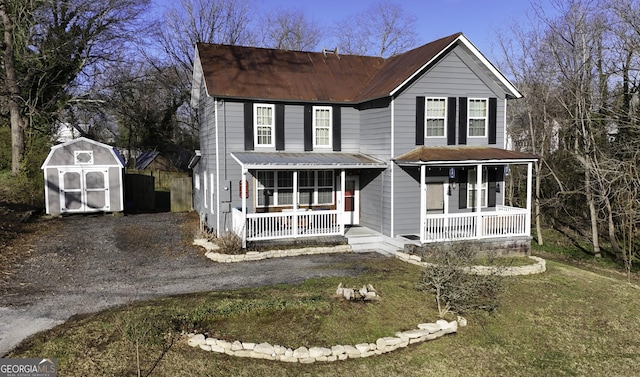 view of front of house with an outdoor structure, driveway, covered porch, and a shed