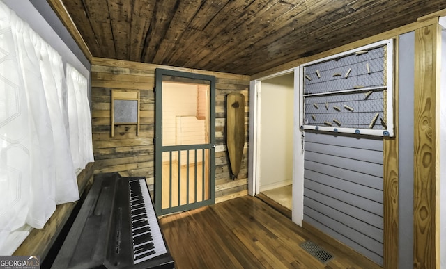 corridor featuring visible vents, wooden walls, wood ceiling, and wood finished floors