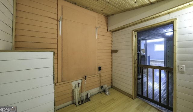 clothes washing area featuring wooden walls, wood ceiling, and light wood-type flooring