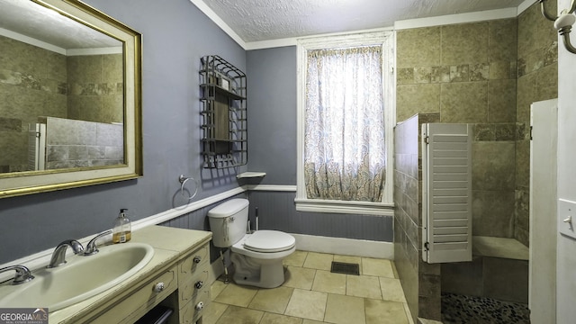 full bathroom with vanity, visible vents, wainscoting, a textured ceiling, and toilet