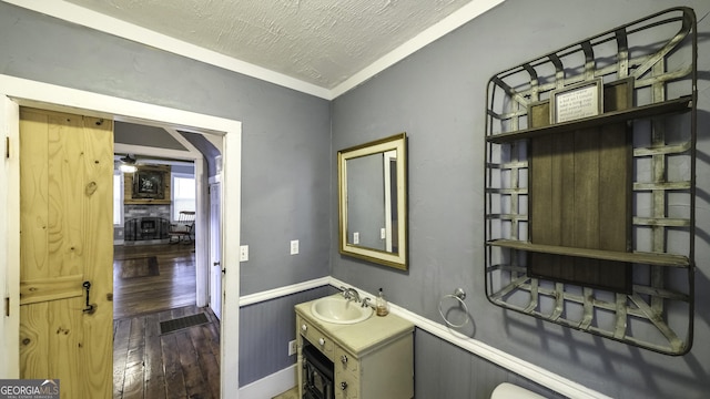 bathroom with hardwood / wood-style floors, a textured ceiling, vanity, and wainscoting