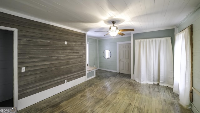 spare room featuring ornamental molding, hardwood / wood-style floors, a ceiling fan, and wood walls