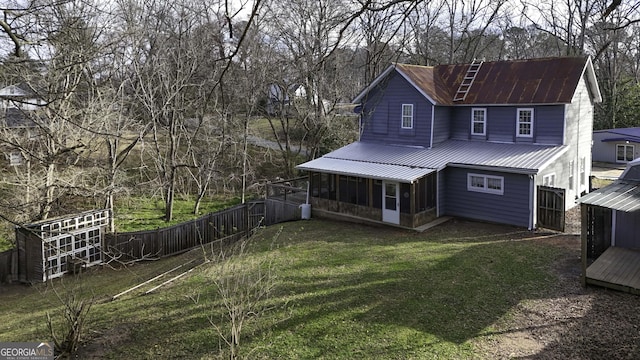 back of house with a fenced backyard, metal roof, a yard, and a sunroom