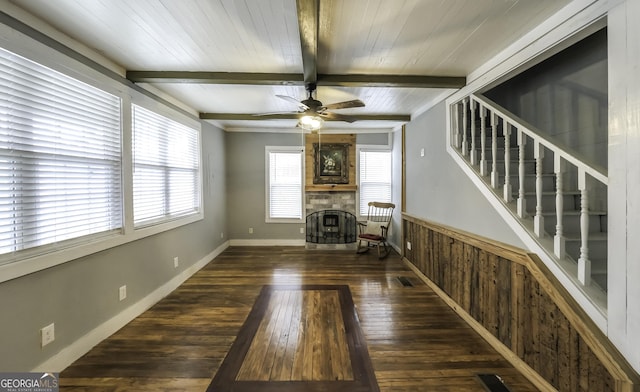 unfurnished living room with stairway, baseboards, beam ceiling, a fireplace, and wood-type flooring