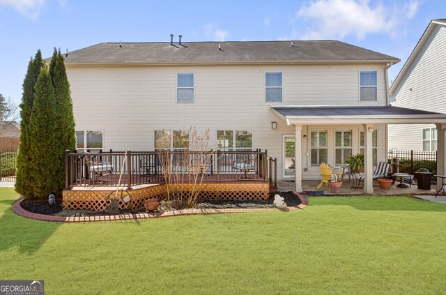 rear view of property with fence, a lawn, a deck, and a patio area