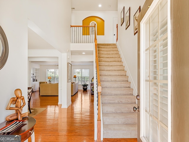 entryway with baseboards, light wood-style flooring, a high ceiling, recessed lighting, and stairs