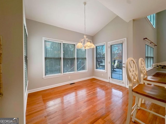 dining space with visible vents, baseboards, lofted ceiling, wood finished floors, and a notable chandelier