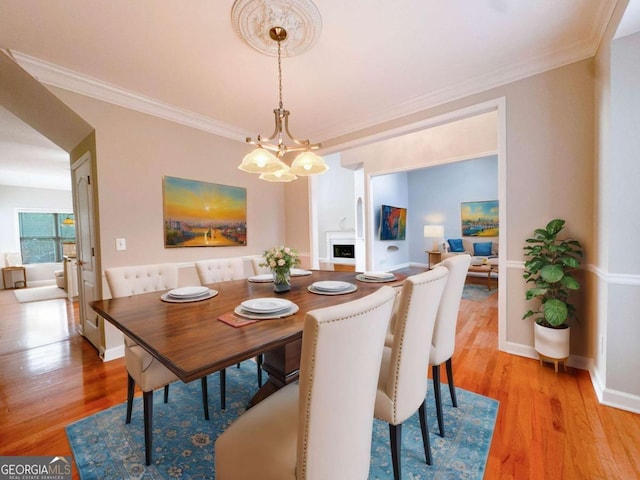 dining space featuring a chandelier, light wood-style flooring, and ornamental molding