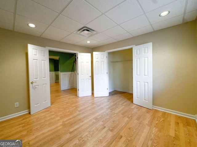 unfurnished bedroom featuring light wood finished floors, visible vents, baseboards, and a drop ceiling