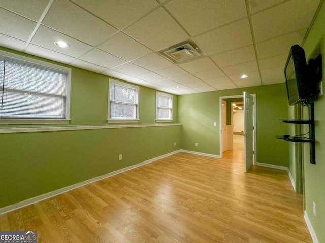 unfurnished room featuring a paneled ceiling, light wood-style floors, visible vents, and baseboards