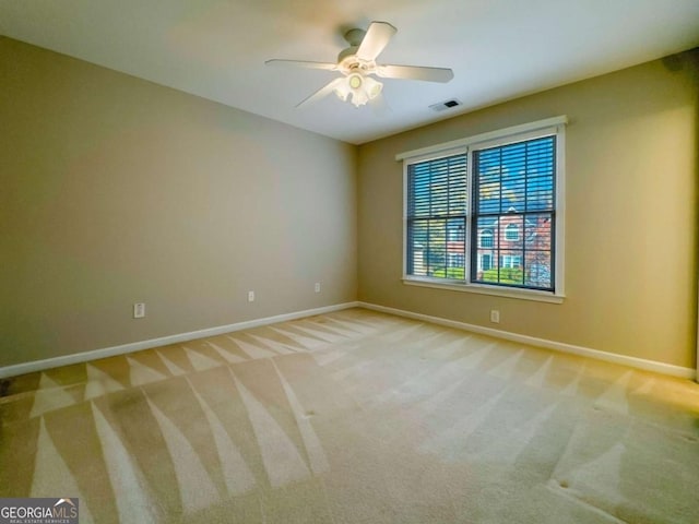 empty room with visible vents, light colored carpet, baseboards, and ceiling fan