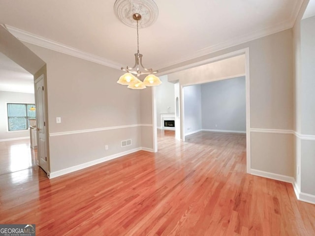 interior space featuring crown molding, light wood-style flooring, baseboards, and a chandelier