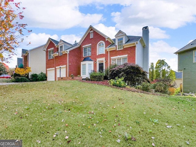 traditional-style house featuring brick siding, an attached garage, a chimney, and a front yard