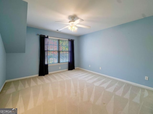 empty room featuring baseboards, light carpet, and ceiling fan