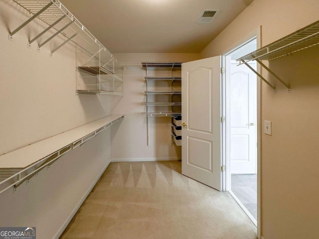 walk in closet with visible vents and light carpet