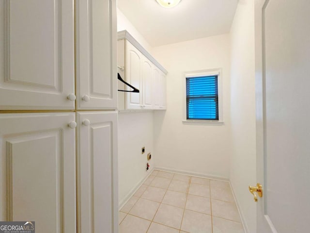 clothes washing area featuring light tile patterned flooring, cabinet space, electric dryer hookup, and baseboards