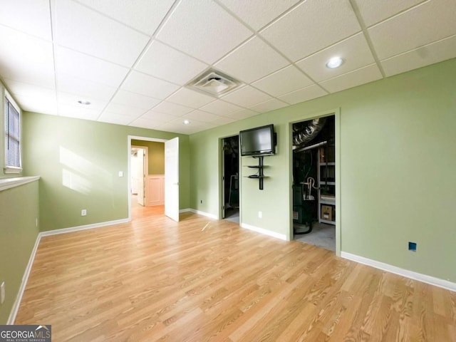 unfurnished room with a drop ceiling, visible vents, baseboards, and wood finished floors