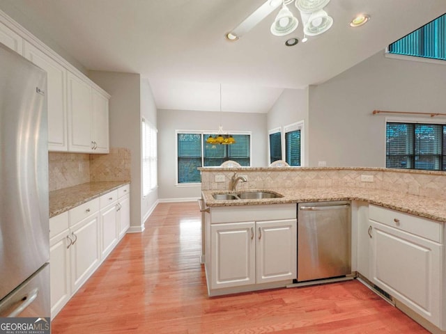 kitchen with a sink, vaulted ceiling, white cabinets, appliances with stainless steel finishes, and light wood-type flooring