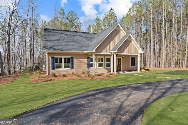 view of front of home featuring a porch, roof with shingles, a front yard, and board and batten siding